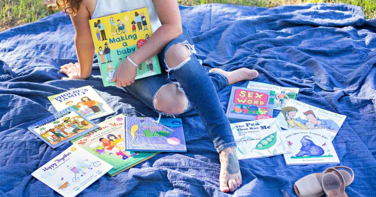 person is sitting on a blue blanket with children books about reproduction information